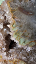 Close-up of a natural crystal geode specimen with clear quartz points, pale green inner chambers, and brown to tan outer rinds. Item in photo is not item(s) for sale. 