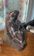 Uruguayan black quartz cut base with vibrant red/yellow/orange agate banding and calcite growth. 