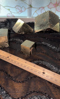 Pyrite cube shown with a quarter leaned against it to show the mirror-like surface. 