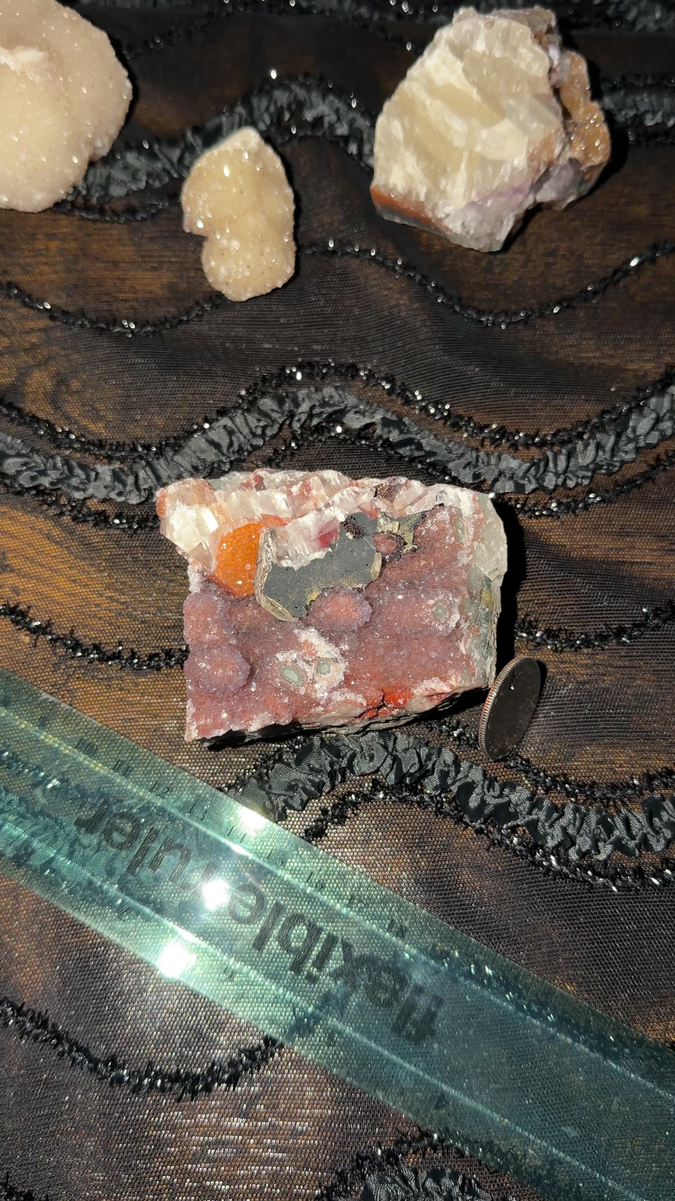 2 inch multi-mineral specimen showing its purple stalactite, orange calcite, red and black hematite formations. 