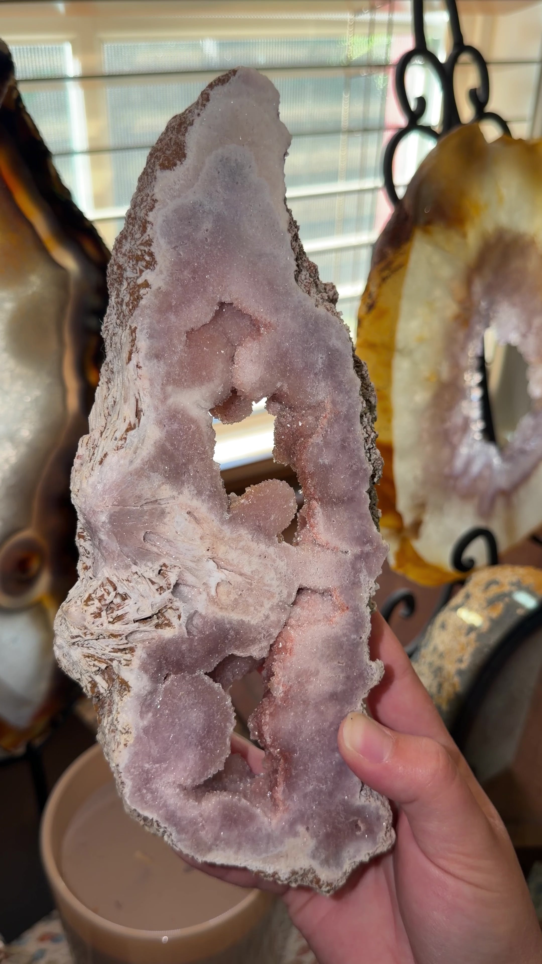 Close up of Brazilian pink amethyst portal featuring two dark pink botryoidal caves. 