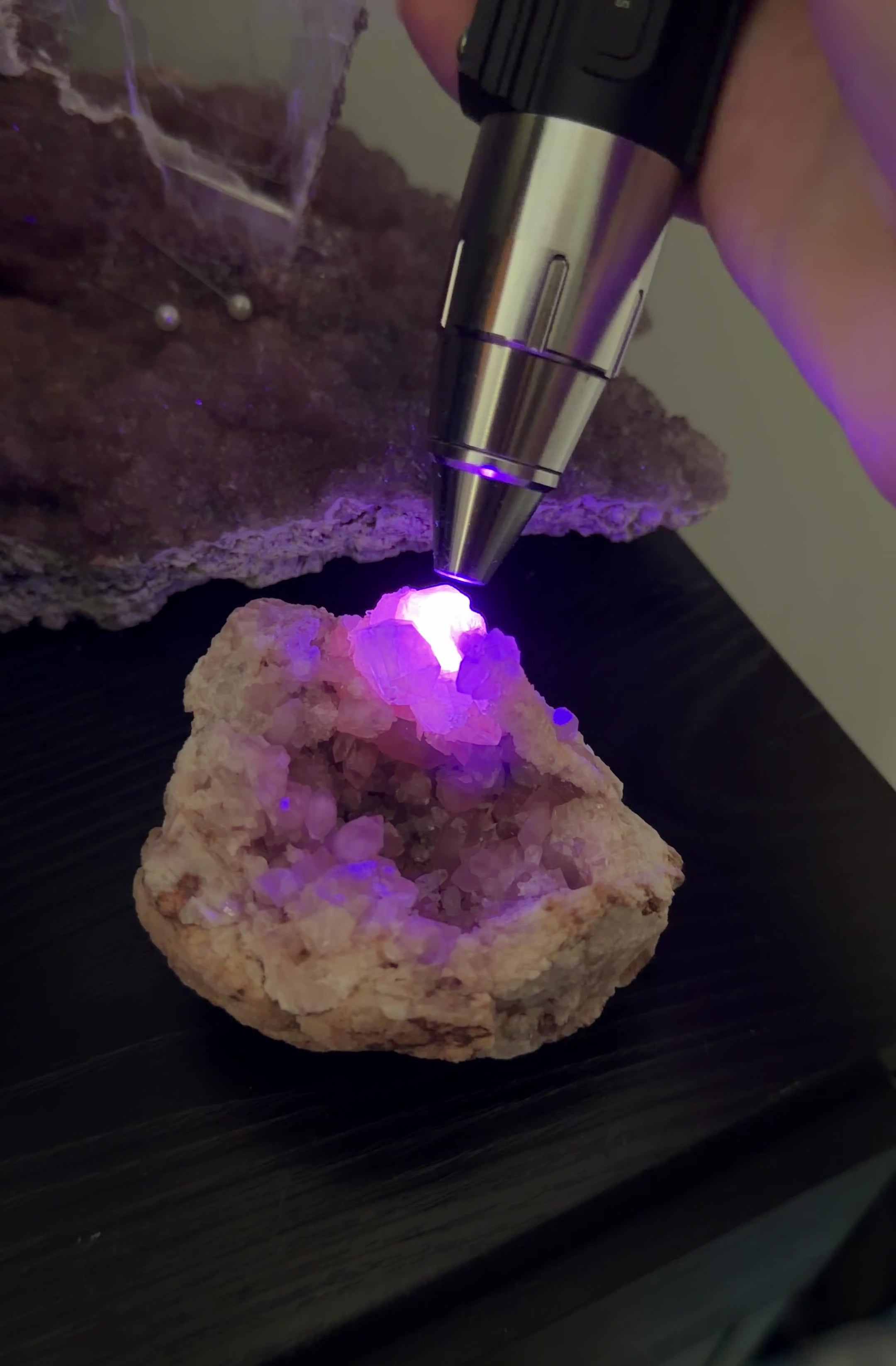 Geode shown under UV light with the calcite formation glowing with a light orange tone. 
