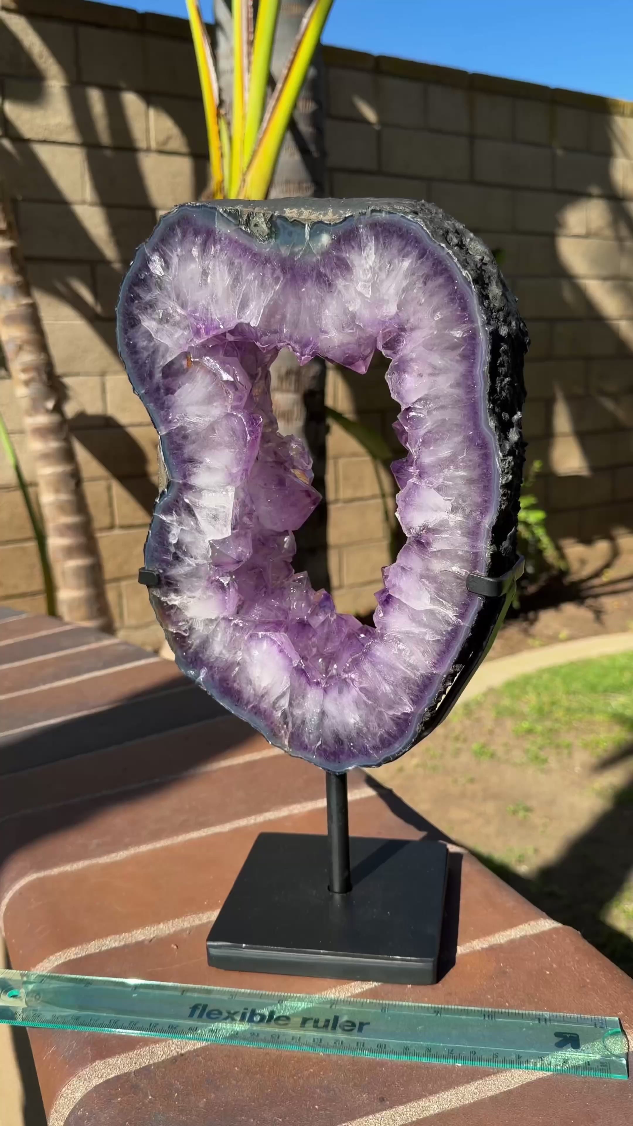 Large Brazilian amethyst portal with deep purple quartz crystals on spinning black display stand. 