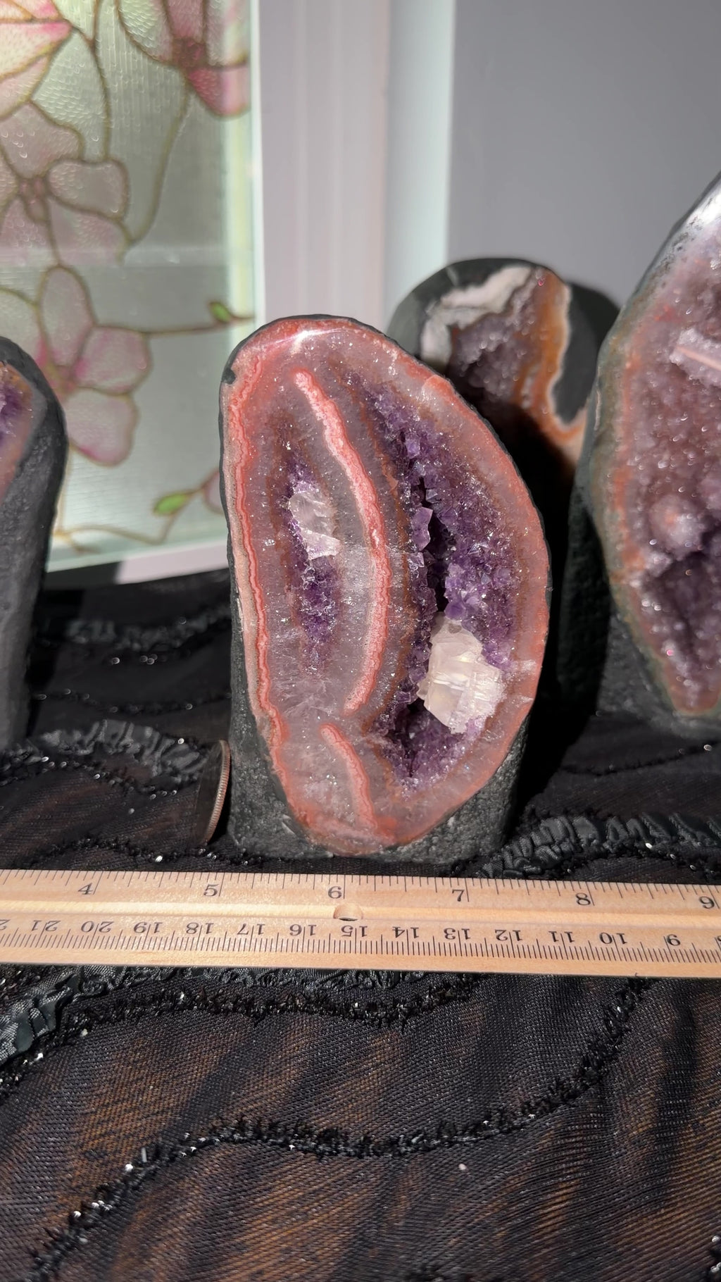 Tall oval shaped purple amethyst with pink/orange/red agate banding and calcite growth geode encased in cement to display as a self standing cathedral.