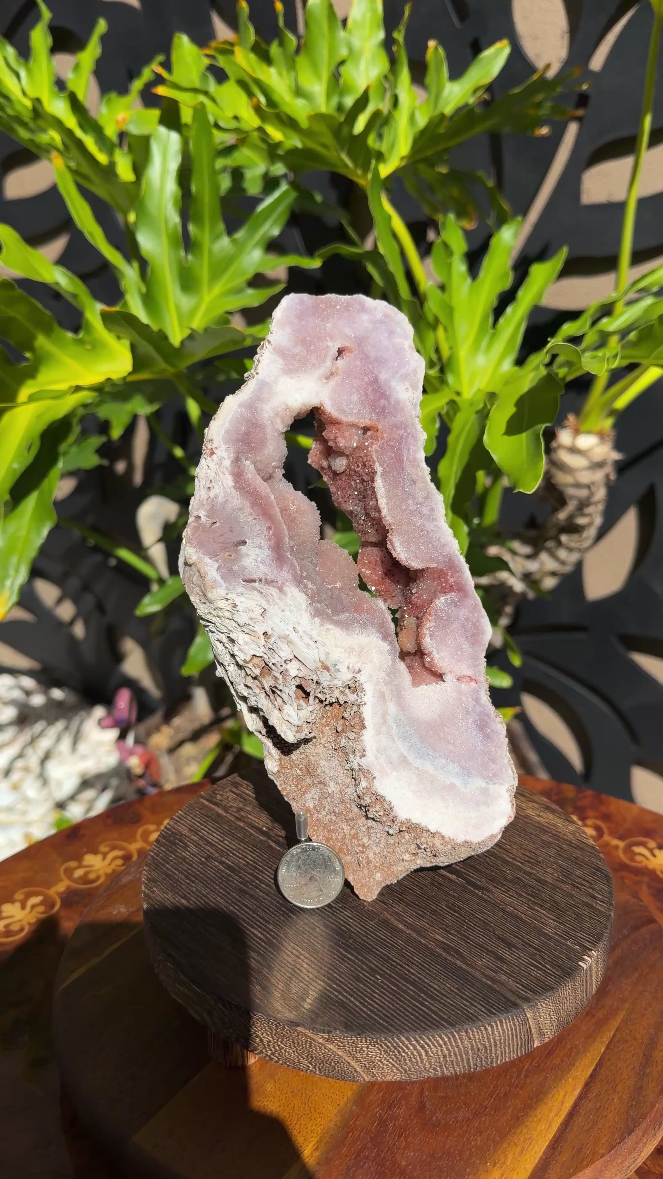 Brazilian pink amethyst portal with soft pink outer banding and dark red botryoidal center. Portal stands upright on a wood/metal stand. 