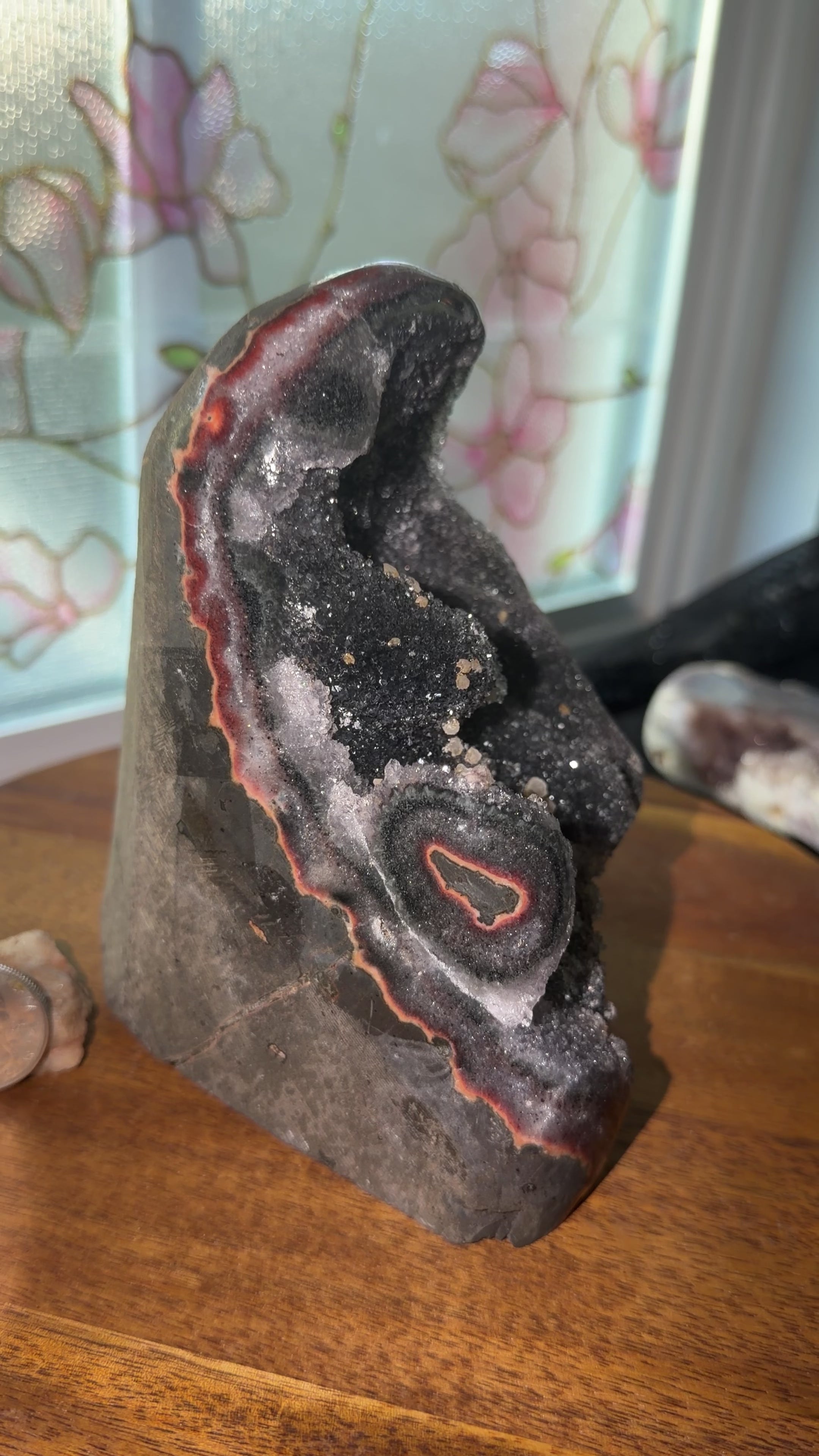 Side view of Uruguayan black quartz cut base with vibrant red/yellow/orange agate banding and calcite growth. 5.5 inch tall, 4.4 inch wide. 