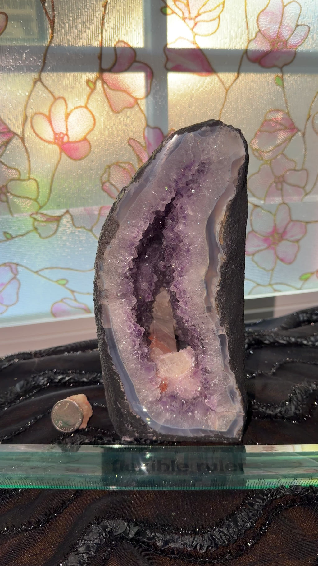 Purple amethyst cathedral with large hexagon log calcite formation inside geode. Geode is encased in cement to display as a self standing cathedral. Features blue agate banding and red hematite inclusions within the calcite.