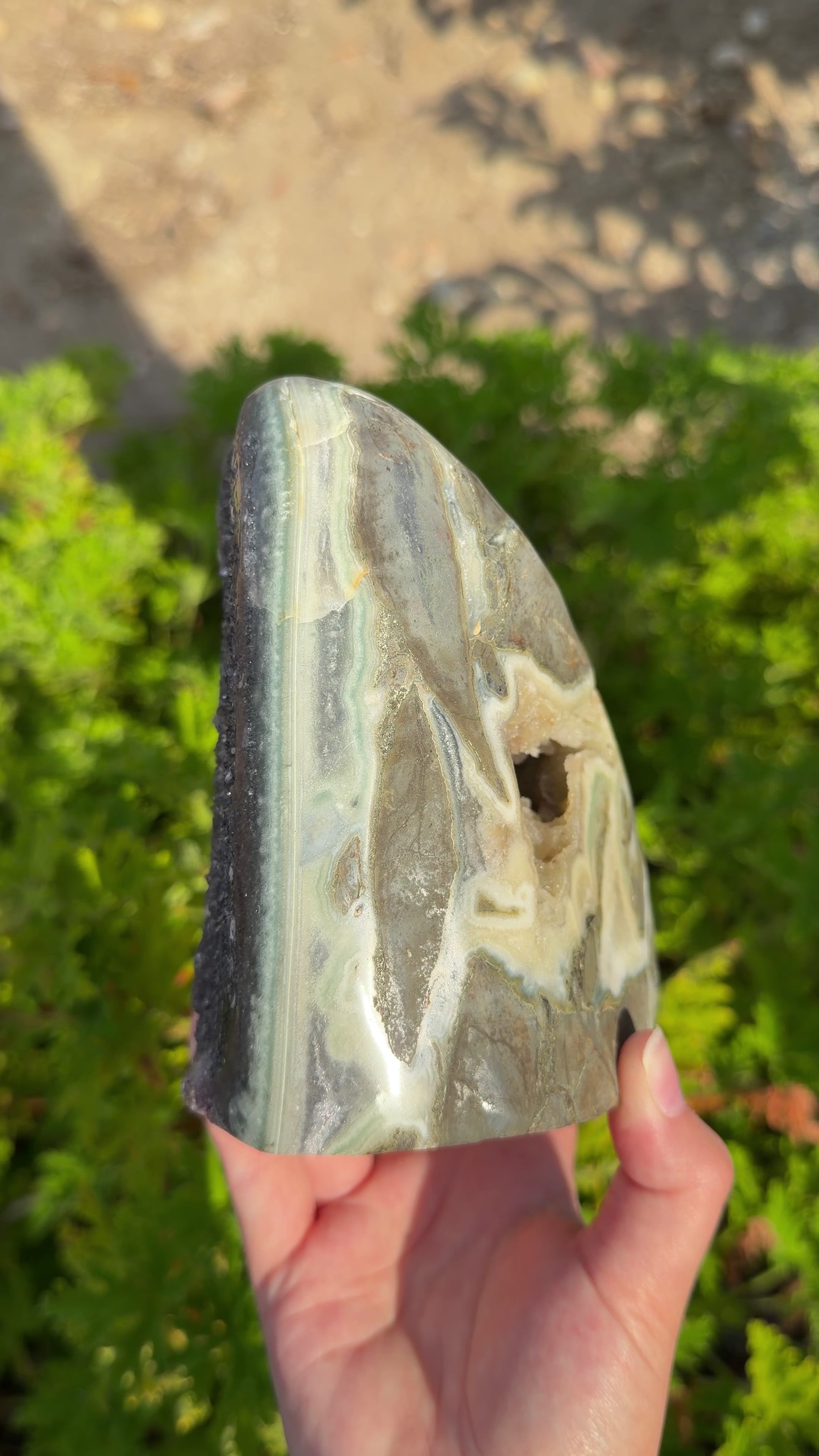 Close up in natural light highlighting the right side of the cut base that features the large amethyst stalactite bed and druzy orange cave from the back point of view.